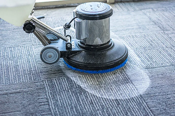 Rotary carpet cleaning machine deep cleaning a grey office carpet