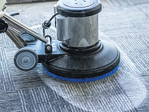Rotary carpet cleaning machine deep cleaning a grey office carpet