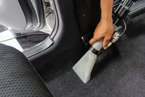Extraction tool deep cleaning the carpet inside a vehicle