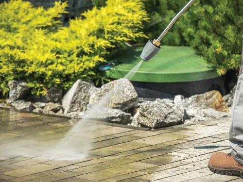 High pressure washer cleaning brick paving on a driveway