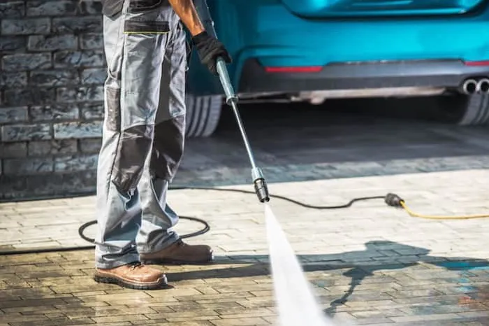 High pressure washer cleaning brick paving on a driveway