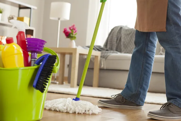 Professional cleaner deep cleaning a living room floor with mop and cleaning supplies