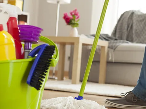 Professional cleaner deep cleaning a living room floor with mop and cleaning supplies