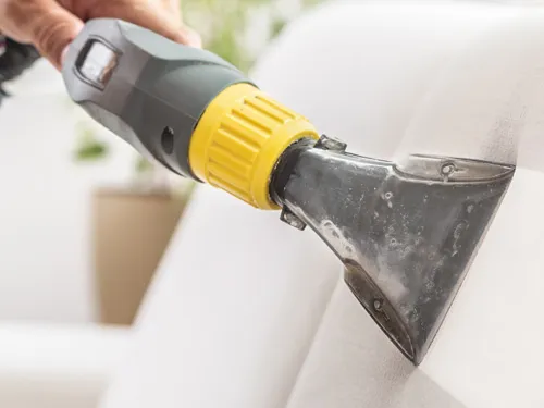 Upholstery extraction tool deep cleaning a white fabric couch