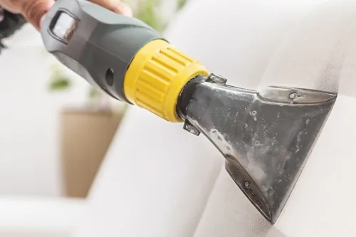 Upholstery extraction tool deep cleaning a white fabric couch